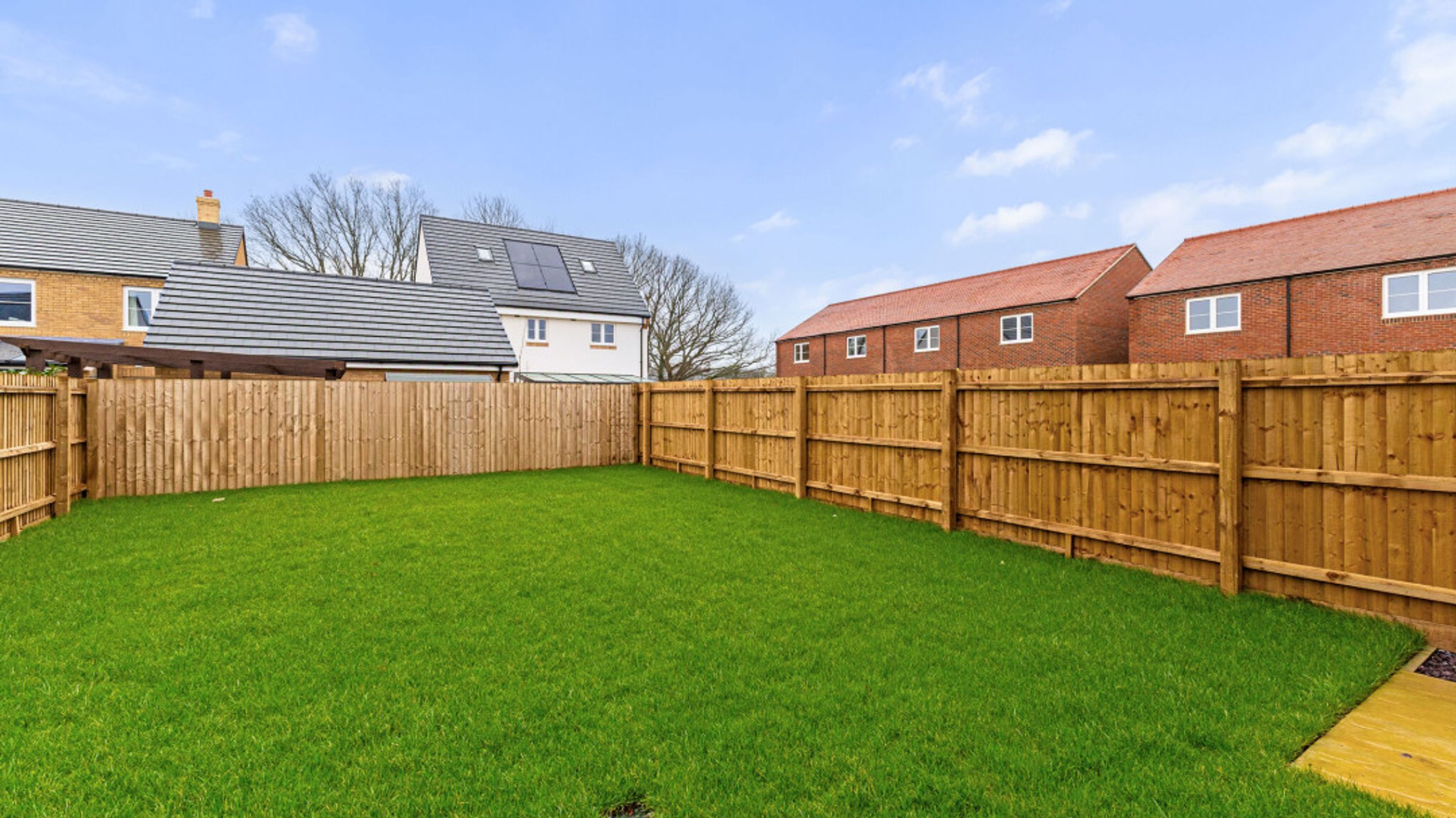 A backyard with a green lawn and a wooden fence.