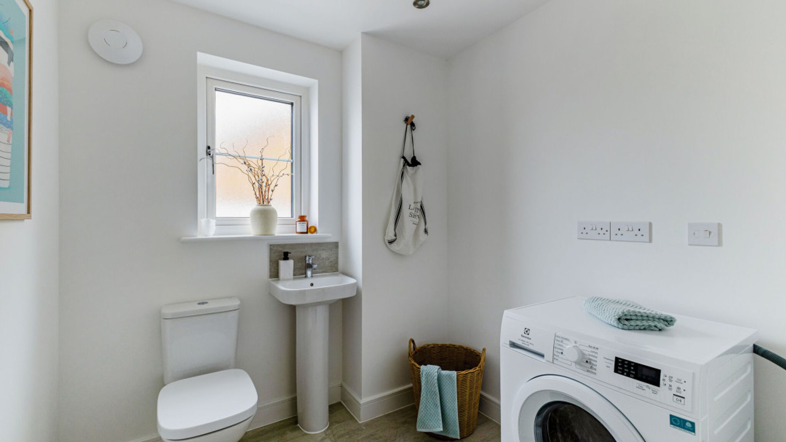 A laundry room with a washing machine, sink, and toilet.