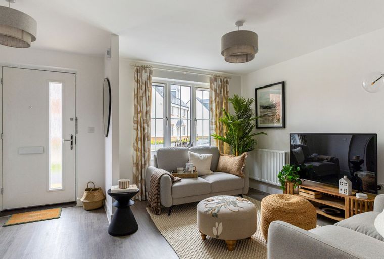A living room with a loveseat, ottoman, and a television.