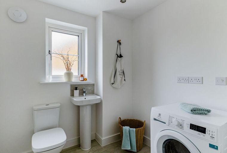 A laundry room with a washing machine, sink, and toilet.