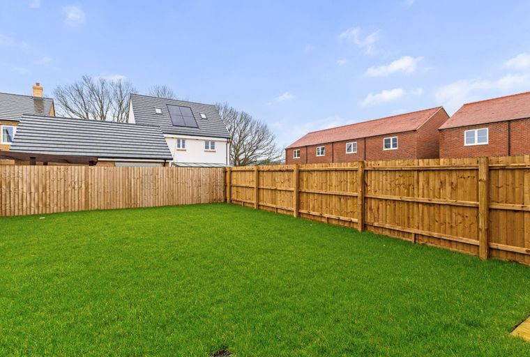 A backyard with a green lawn and a wooden fence.