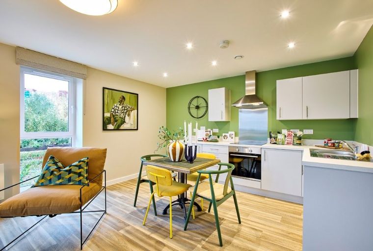 A dining area and kitchen with chairs, a table, and kitchen appliances.