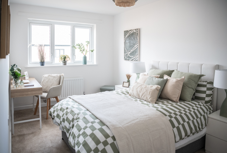 A bedroom with a bed, desk, and window.