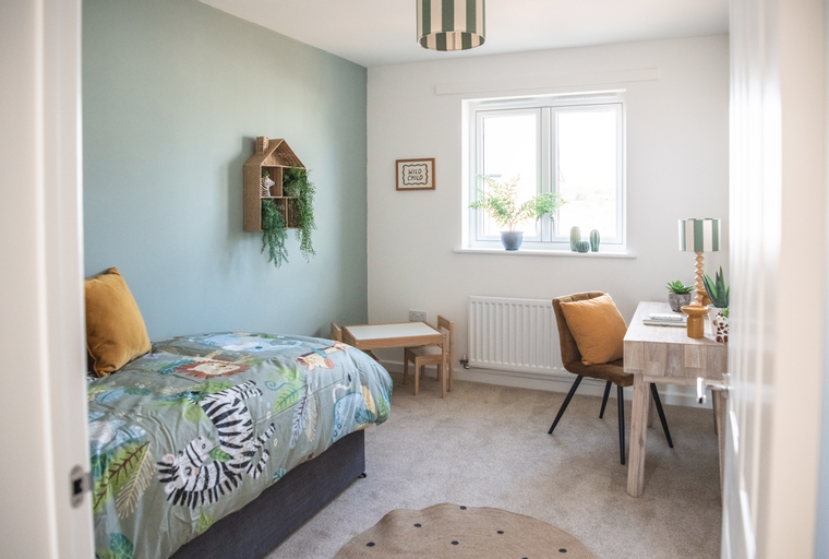 A child's bedroom with a bed, desk, and a small table and chairs.