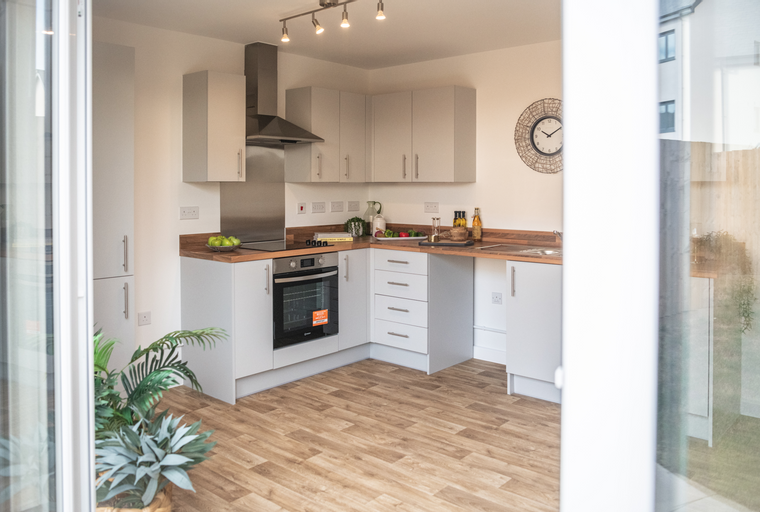 A modern kitchen with grey cabinets, wooden countertops, and a built-in oven.