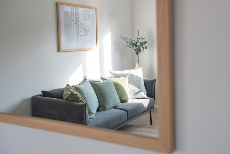 A grey sofa with several decorative pillows in a well-lit room.