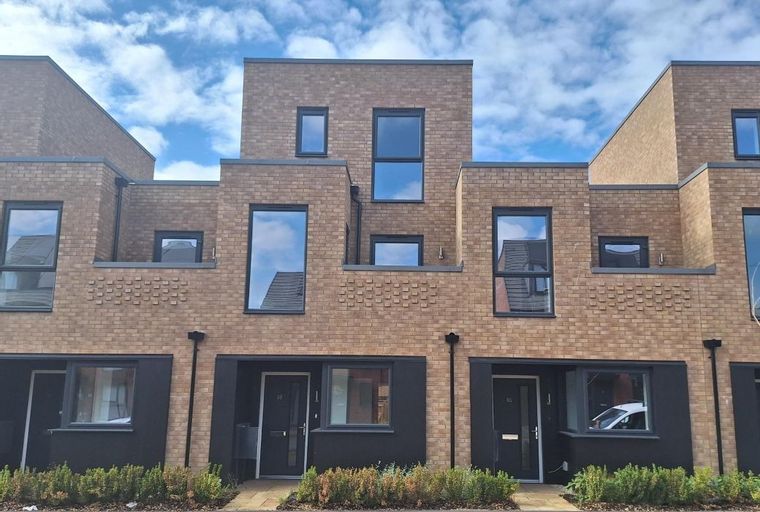 A row of modern brick townhouses with dark window frames and entrances.