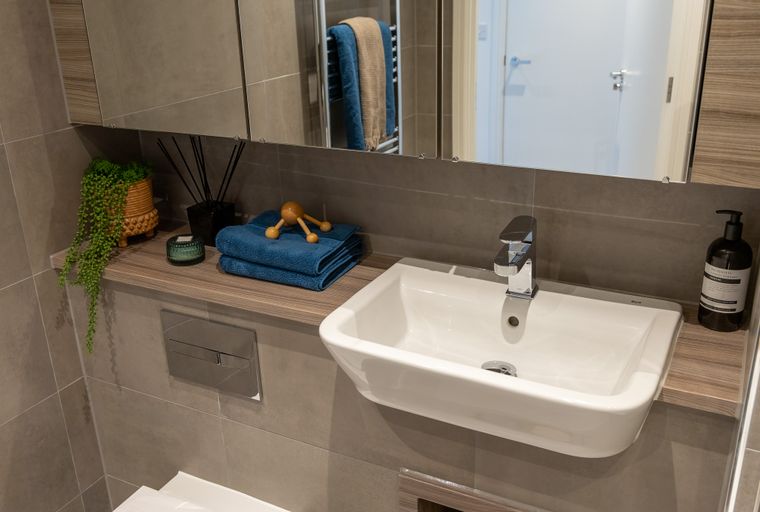 A bathroom vanity with a sink, faucet, and decorative items on a shelf.