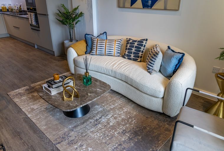 A living room with a curved sofa, coffee table, and a rug.