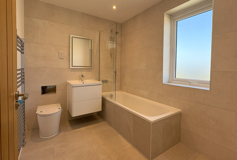 A bathroom with a toilet, a vanity, a bathtub, and a window.