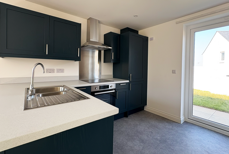 A modern kitchen with dark cabinets, a sink, and a stove.