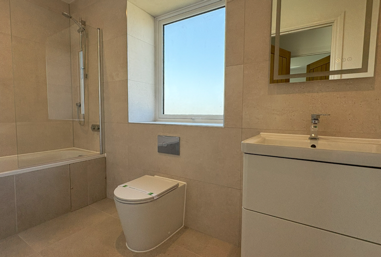 A bathroom with a bathtub, toilet, vanity, and a mirror.