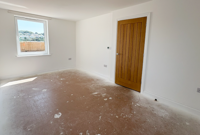 A room with a window, a wooden door, and a floor covered in protective material.