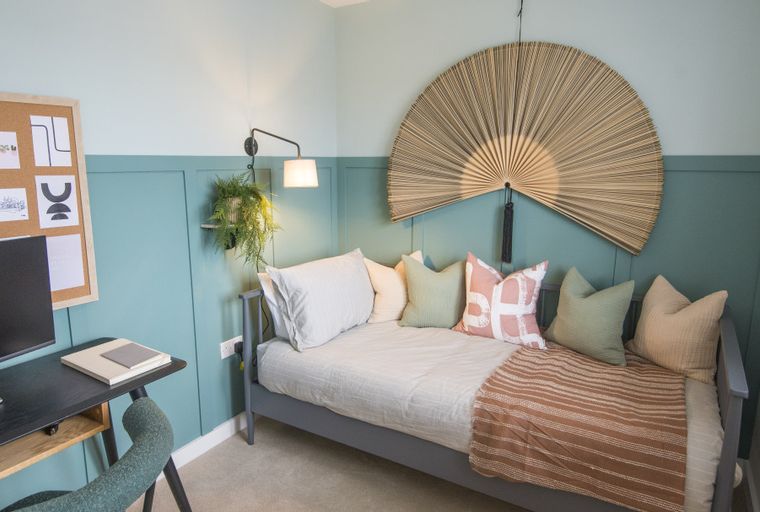 A bedroom with a daybed, desk, and wall art.