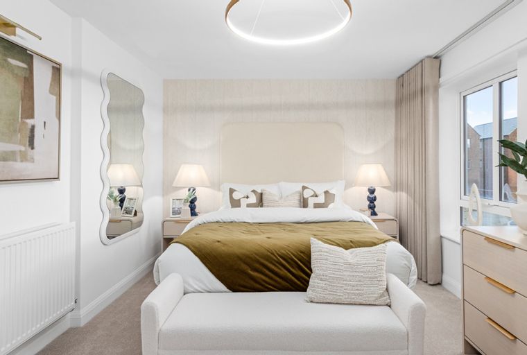 A bedroom with a bed, bedside tables, lamps, and a mirror.