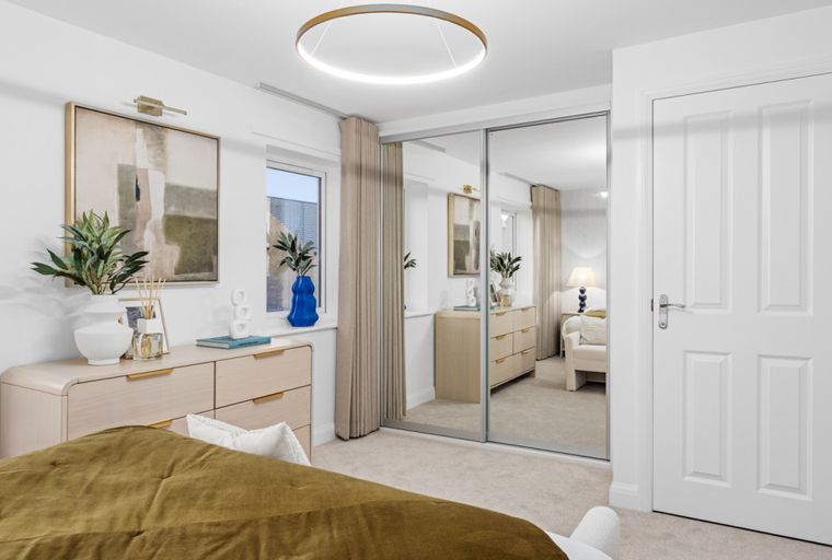 A bedroom with a bed, dresser, mirror wardrobe, and a door.