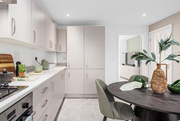 A modern kitchen and dining area with light cabinets, a gas hob, and a dark wood dining table.