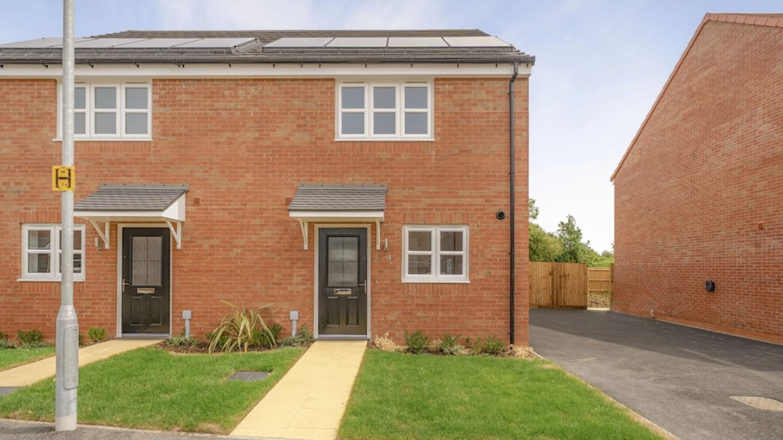 A brick-built semi-detached house with two front doors and multiple windows.