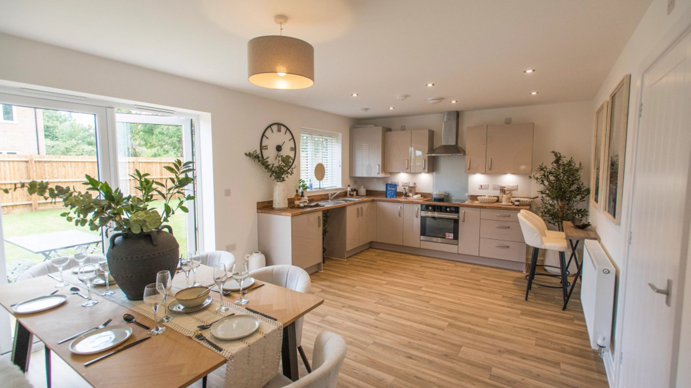 A dining area and kitchen with a table set for a meal and a kitchen island with stools.