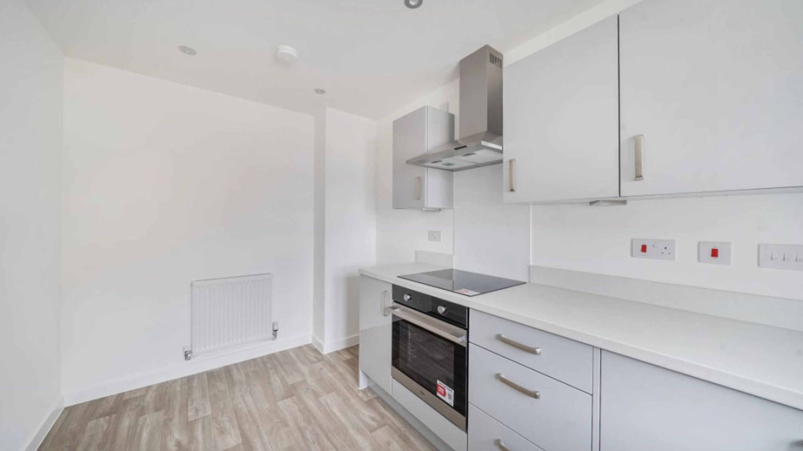 A modern kitchen with grey cabinets, a built-in oven, and a hob.