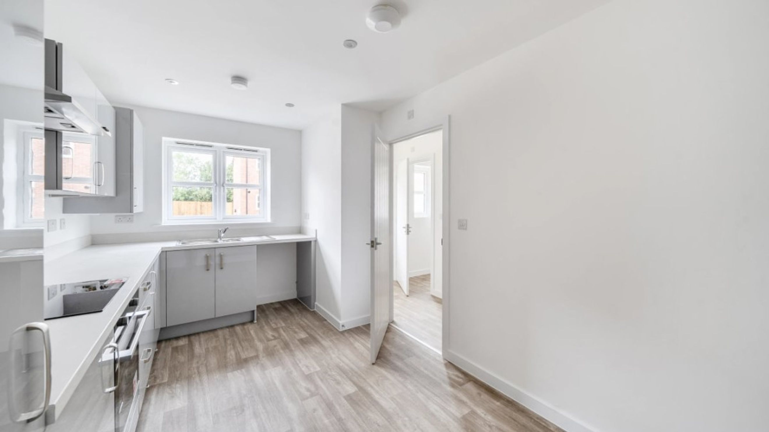 A modern kitchen with grey cabinets, a sink, and windows.
