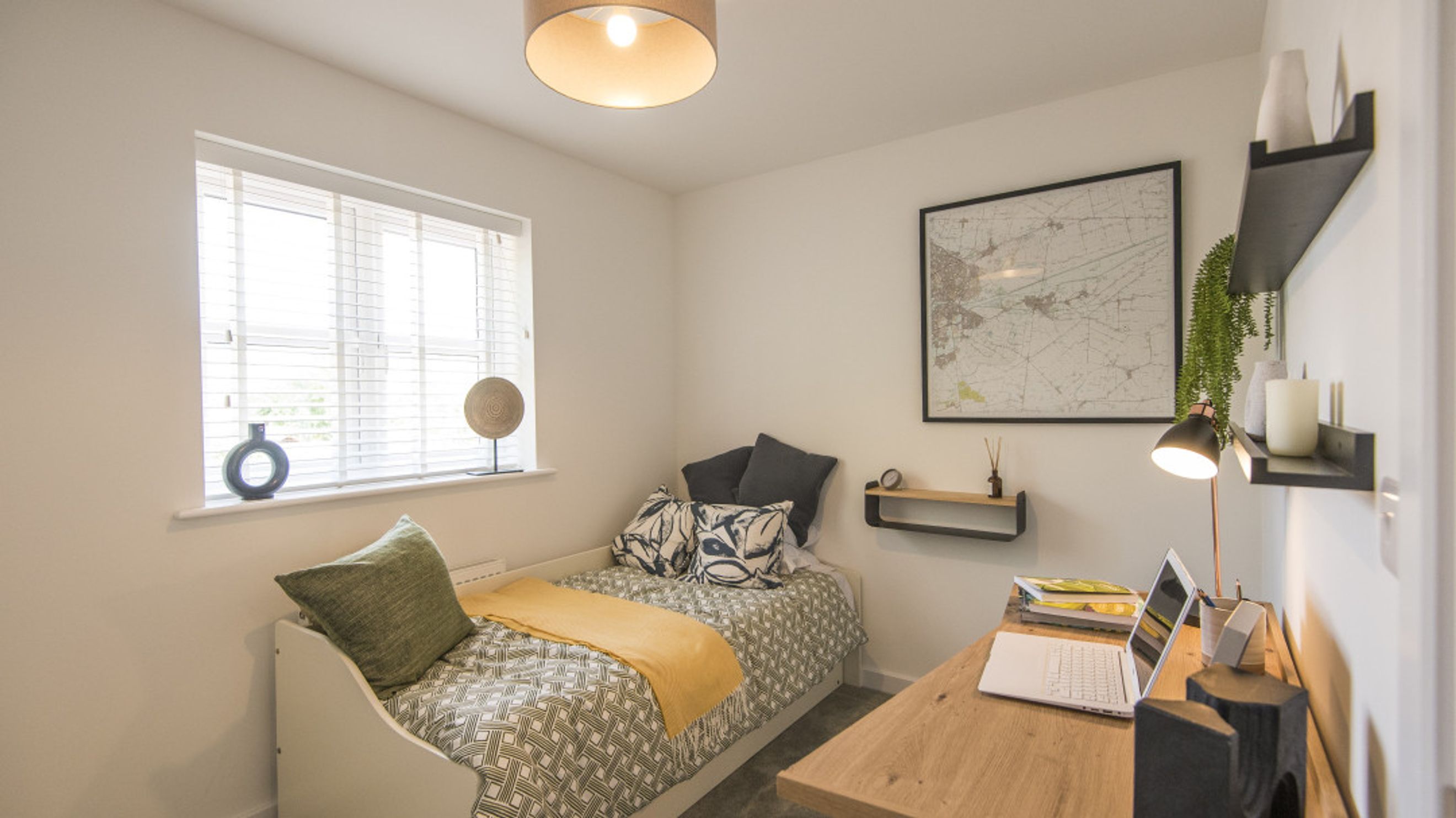 A bedroom with a single bed, a desk, and a window.