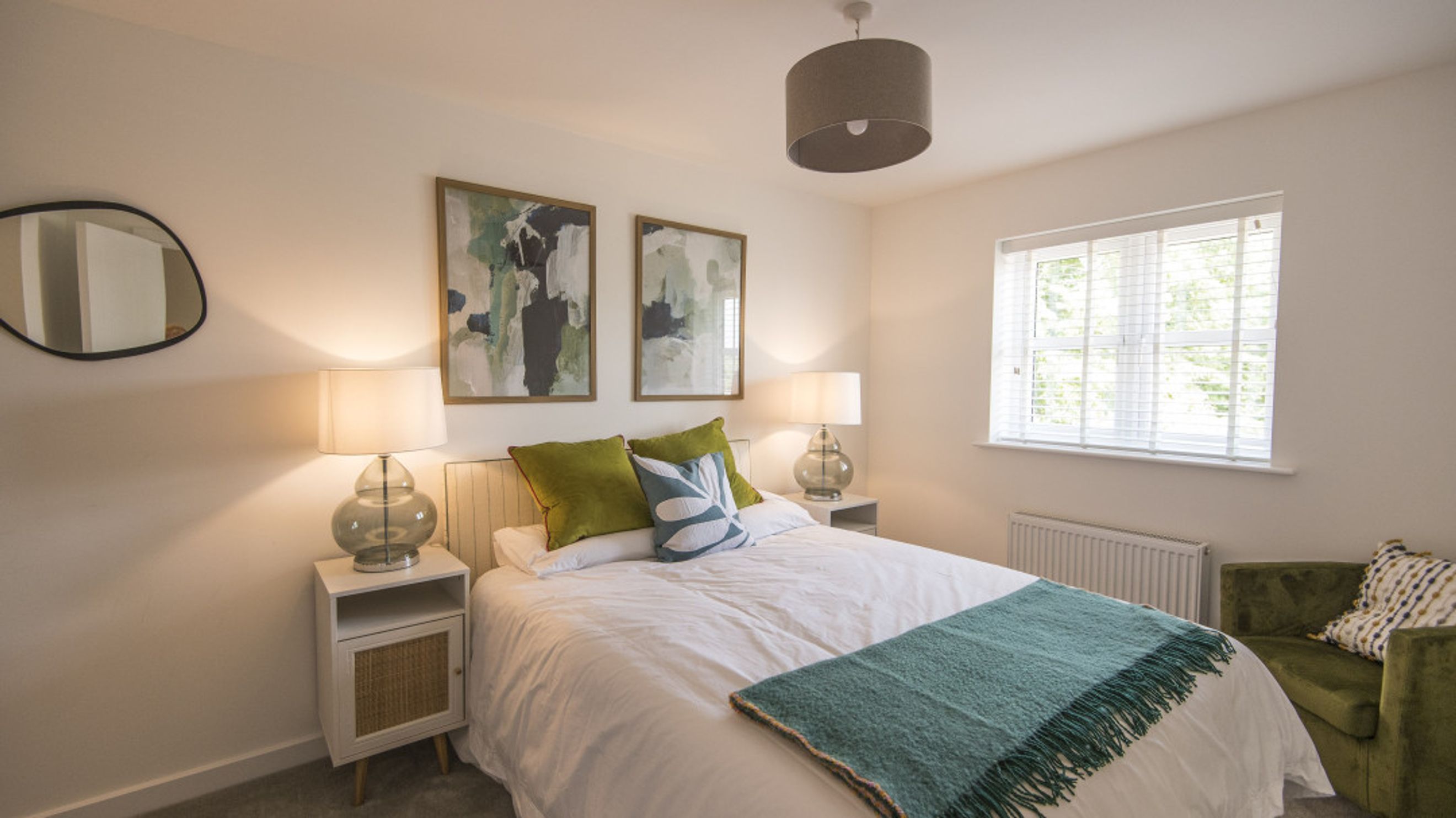 A bedroom with a bed, pillows, and two framed pictures on the wall.