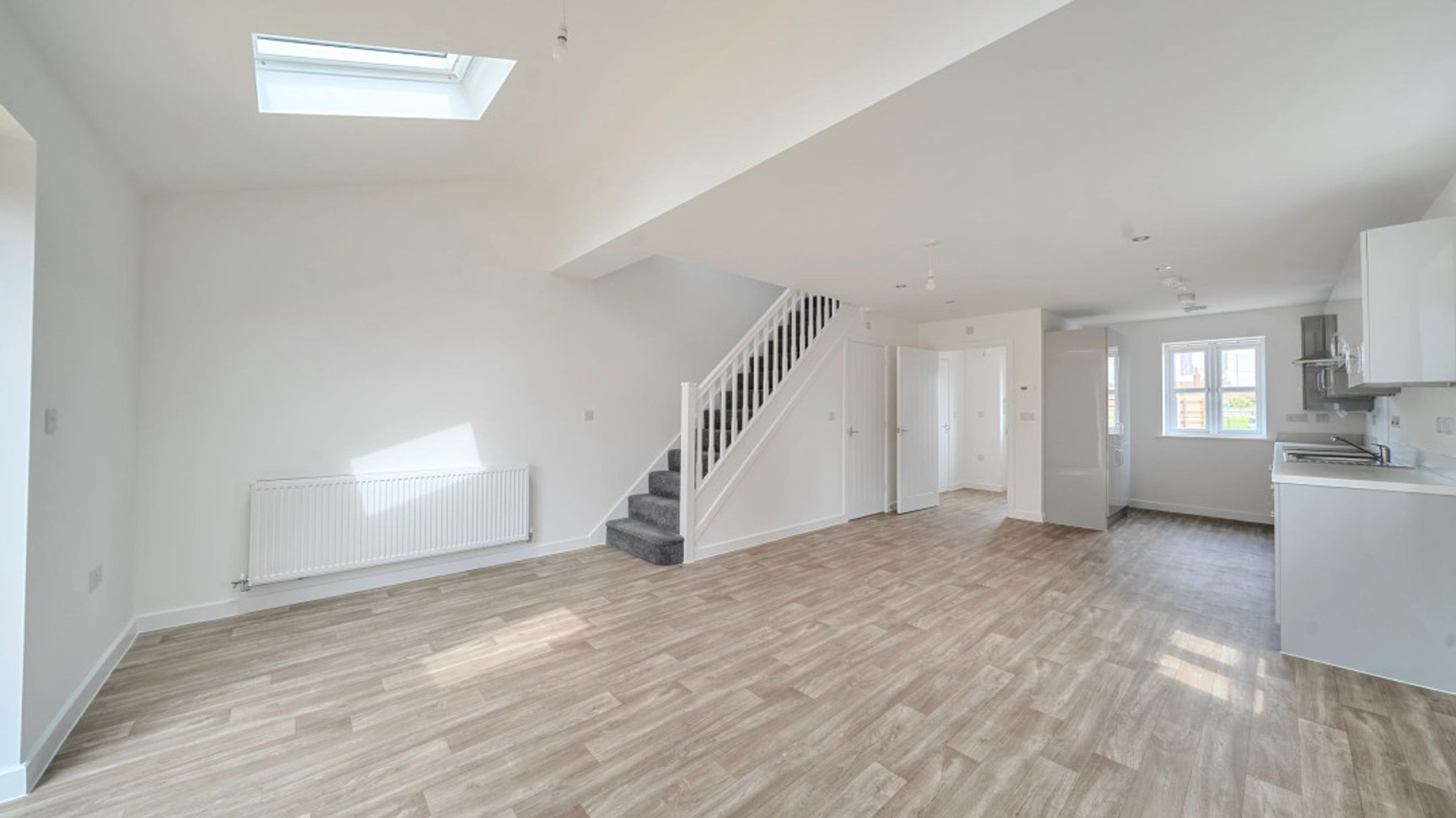 A spacious open-plan living area with a staircase and a kitchen.