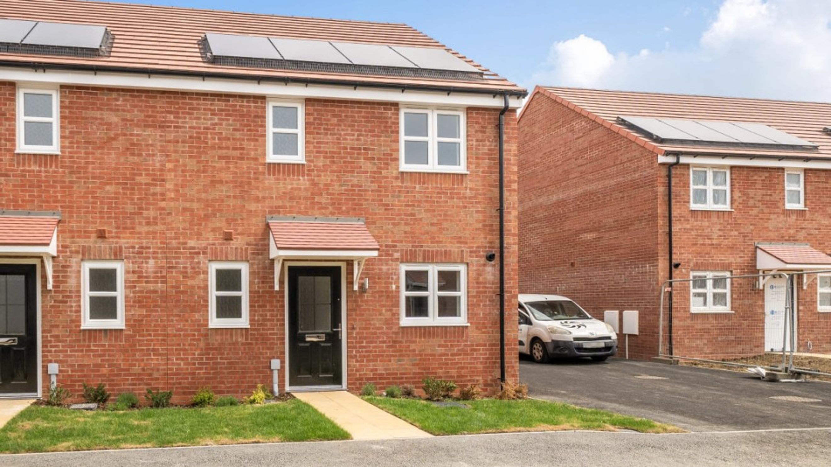 A brick townhouse with solar panels on the roof and white-framed windows.