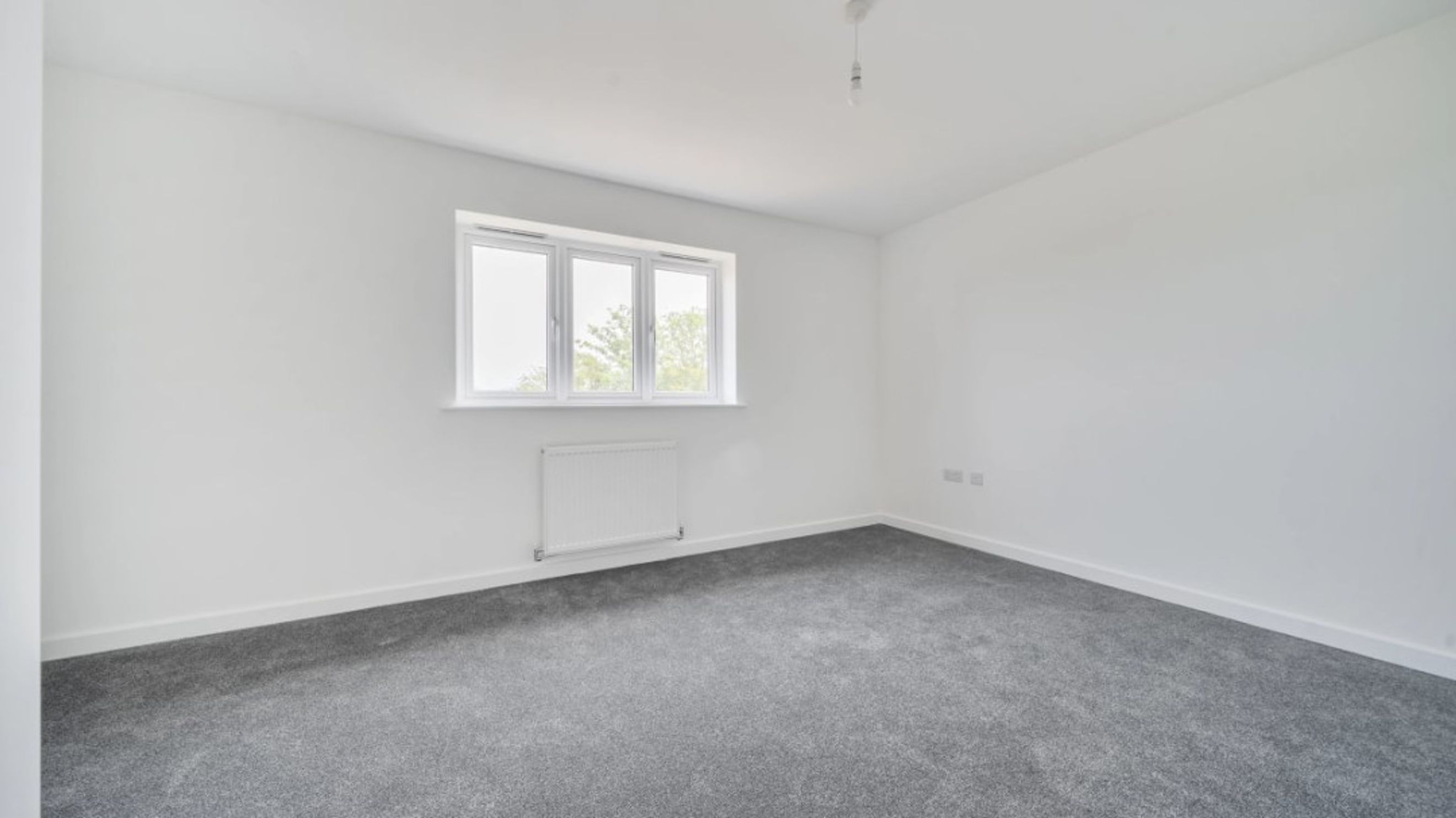 A bedroom with a window and a radiator.
