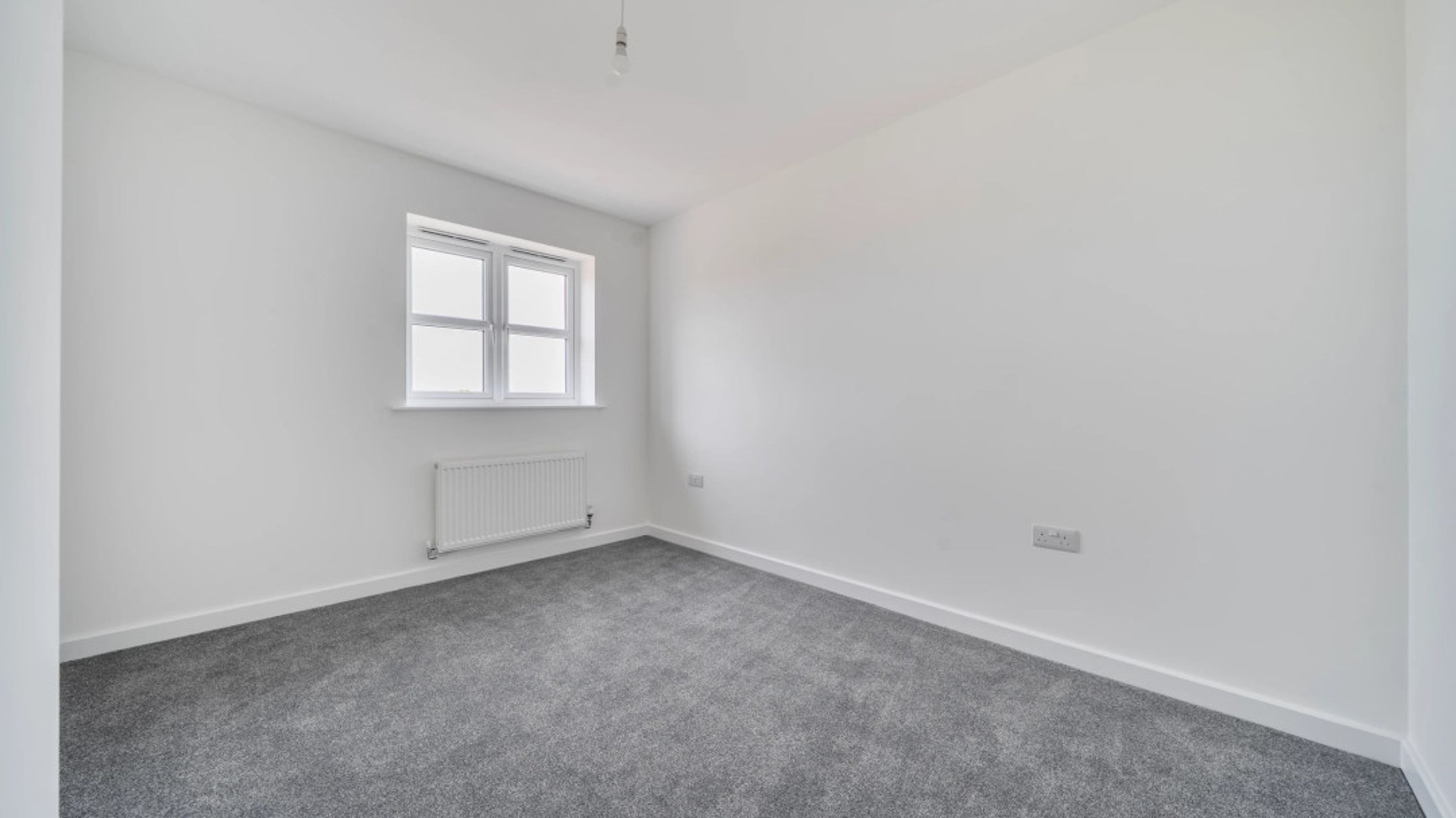 A bedroom with a window and a radiator.