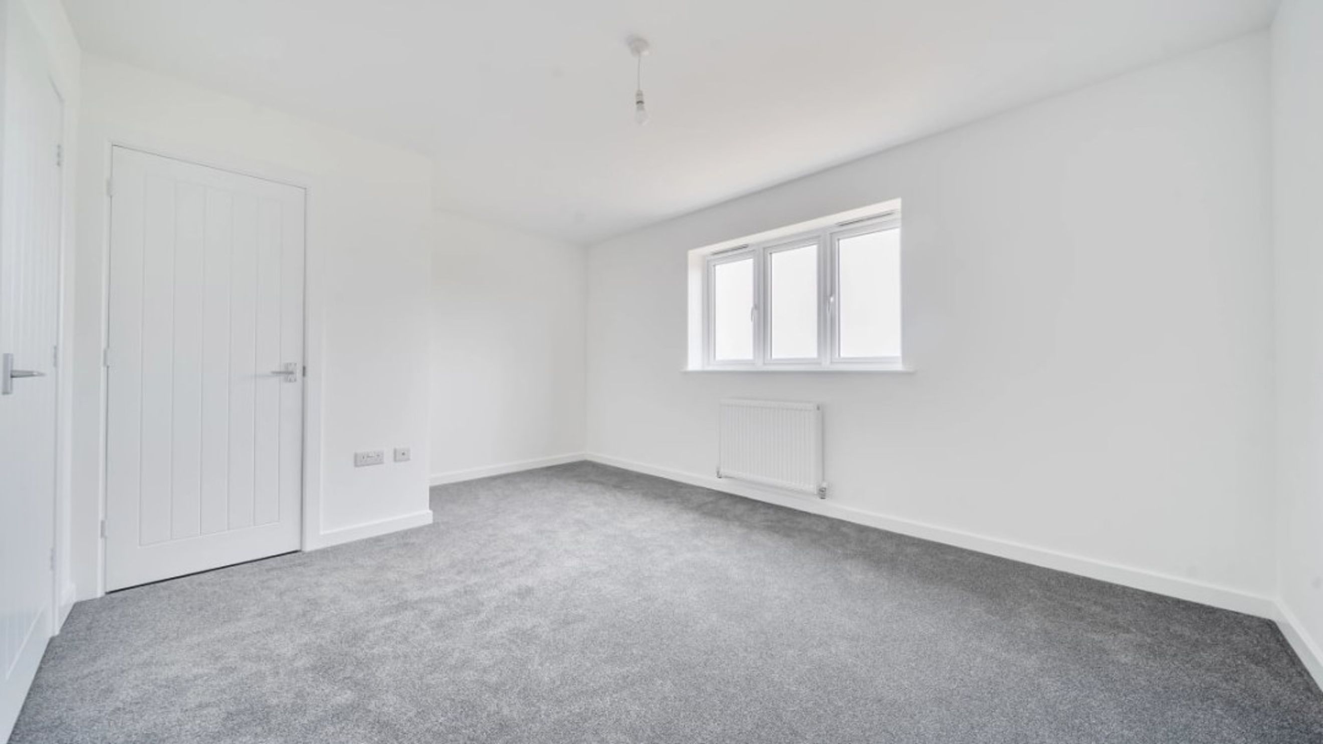 A bedroom with a door, a window, and a radiator.