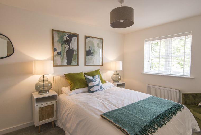 A bedroom with a bed, pillows, and two framed pictures on the wall.