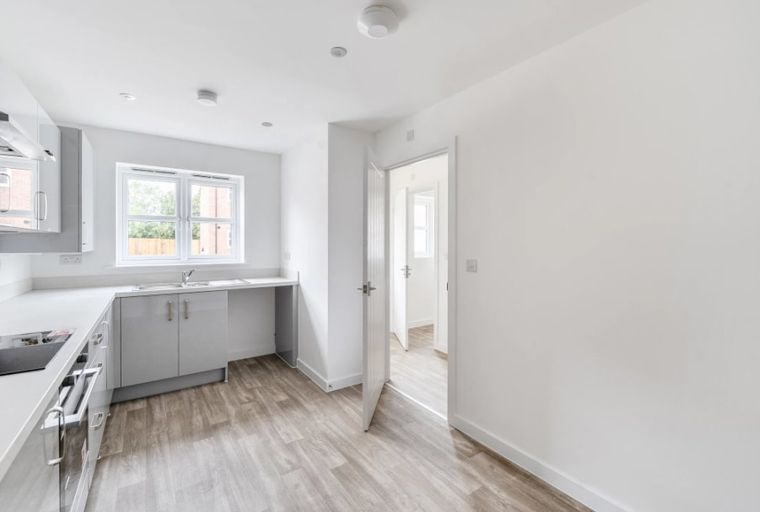 A modern kitchen with grey cabinets, a sink, and windows.