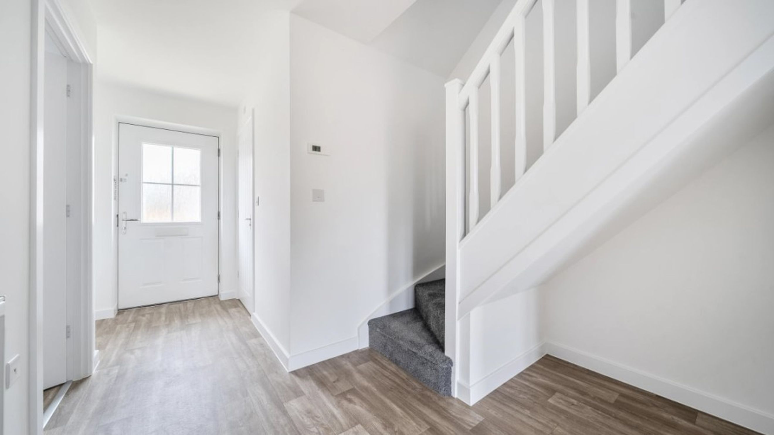 A hallway with a front door and a staircase.