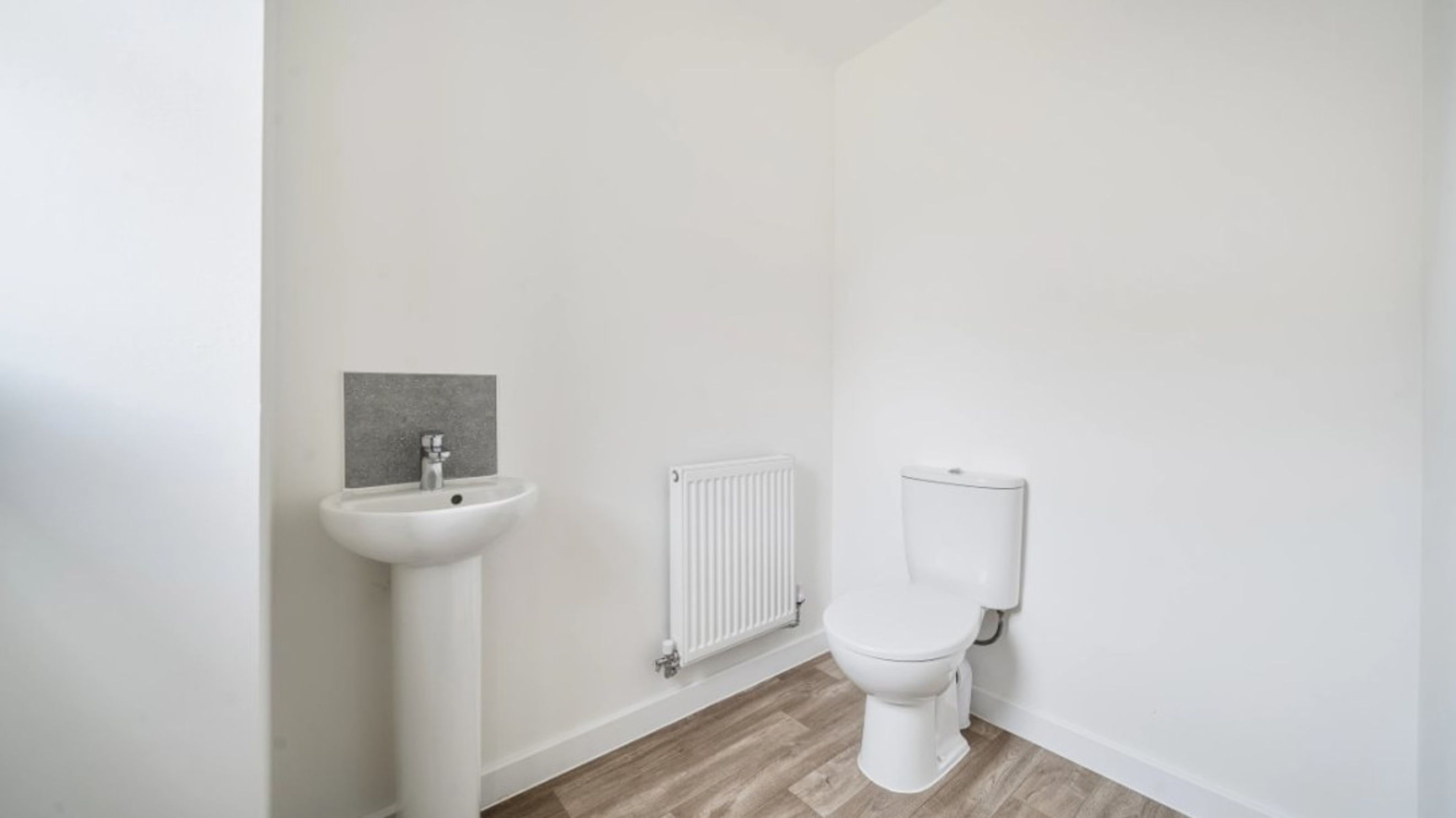 A bathroom with a sink, a radiator, and a toilet.