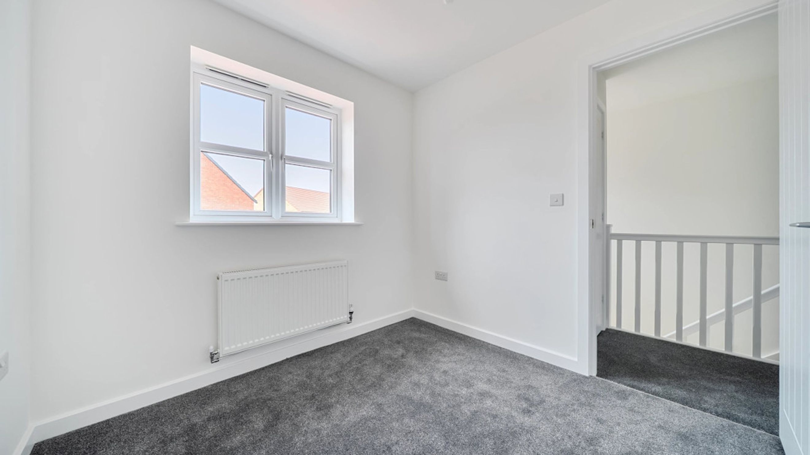 A room with a window, radiator, and a doorway leading to a staircase.