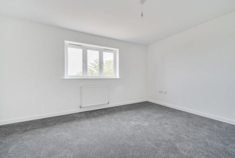 A bedroom with a window and a radiator.