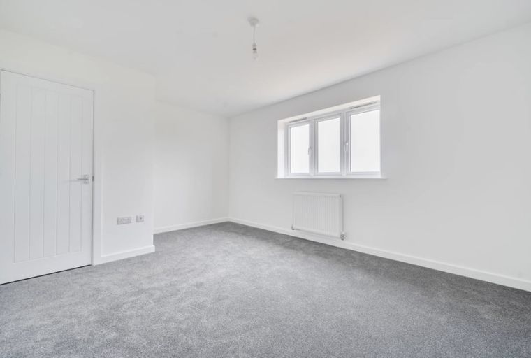 A bedroom with a door, a window, and a radiator.
