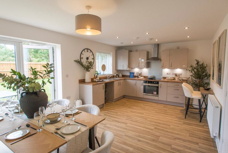 A dining area and kitchen with a table set for a meal and a kitchen island with stools.
