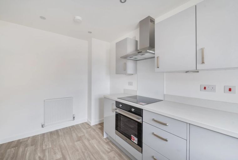 A modern kitchen with grey cabinets, a built-in oven, and a hob.