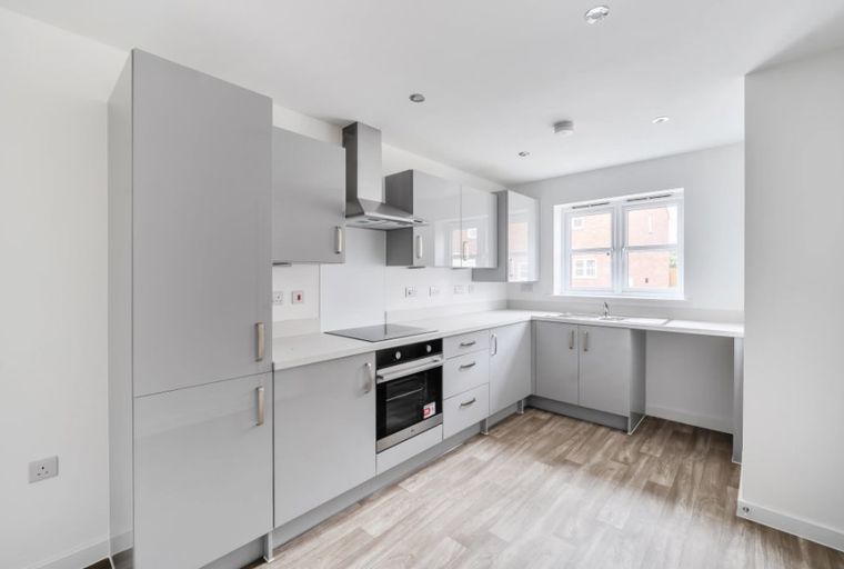 A modern kitchen with grey cabinets, a built-in oven, and a window.
