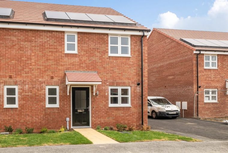 A brick townhouse with solar panels on the roof and white-framed windows.