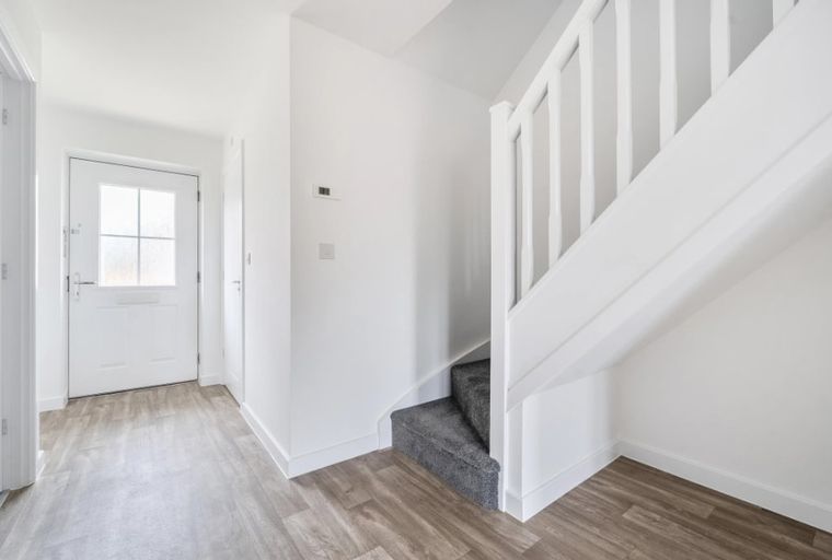 A hallway with a front door and a staircase.