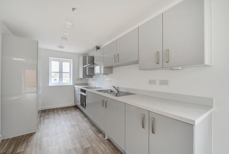 A modern kitchen with grey cabinets, a sink, and an oven.