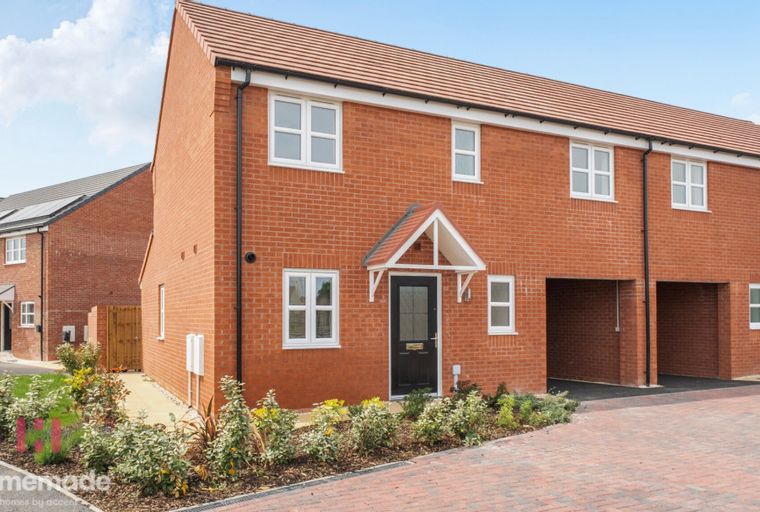 A modern red brick house with white-framed windows and a black front door under a pitched canopy.