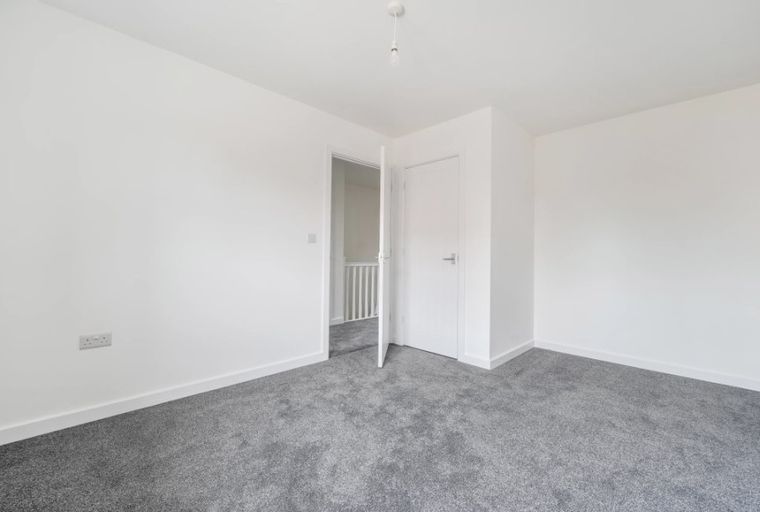 A room with white walls, grey carpet, and two doors.