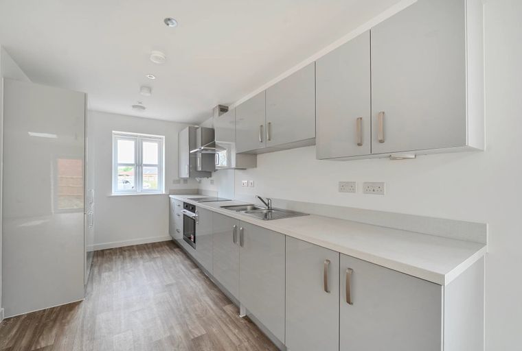 A modern kitchen with light grey cabinets, a countertop, a sink, and a window.
