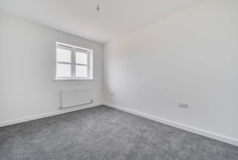 A bedroom with a window and a radiator.
