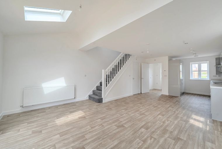 A spacious open-plan living area with a staircase and a kitchen.